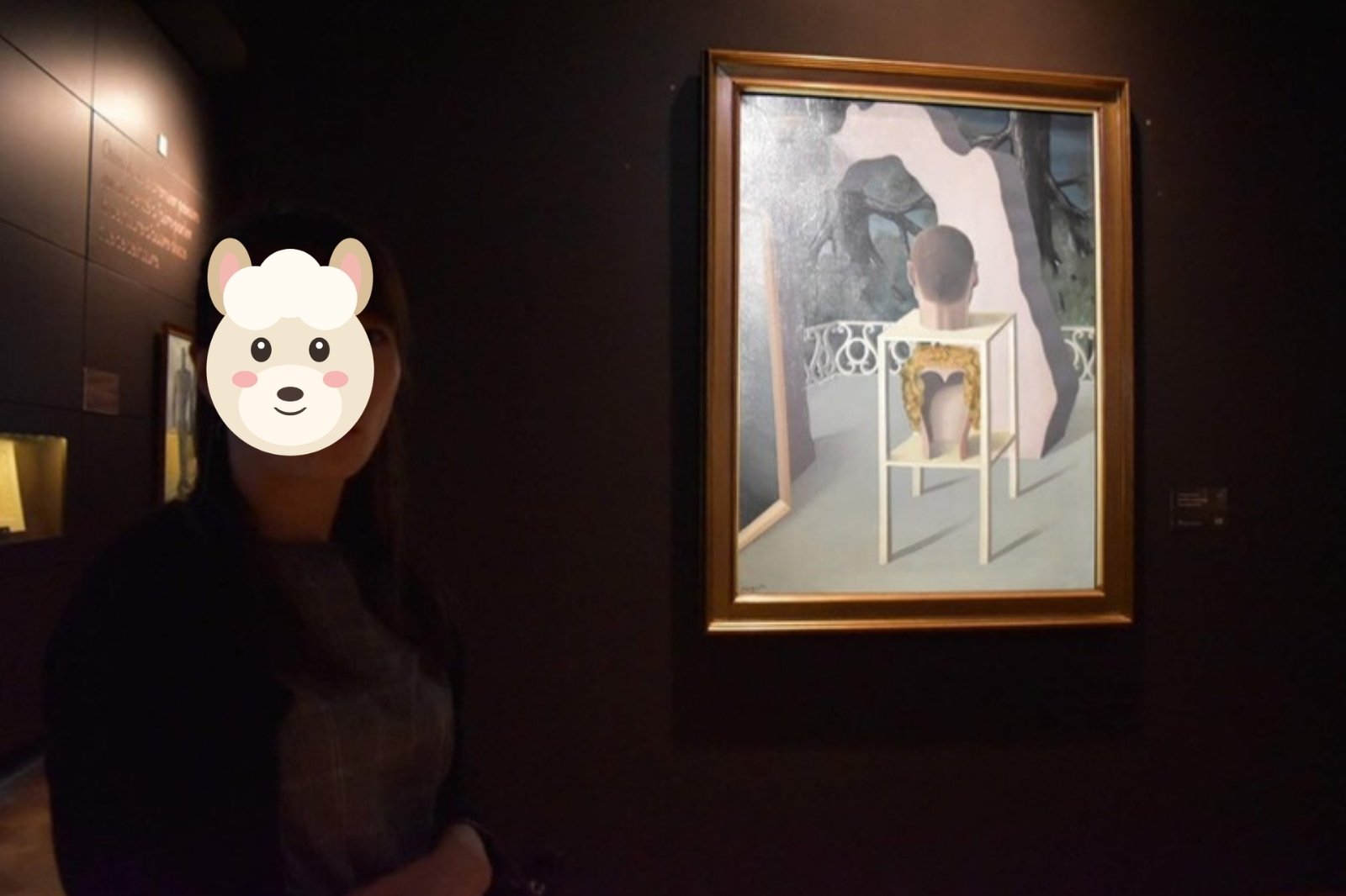 夕暮れの美術館でマグリットの絵画の横に立つ奥さま